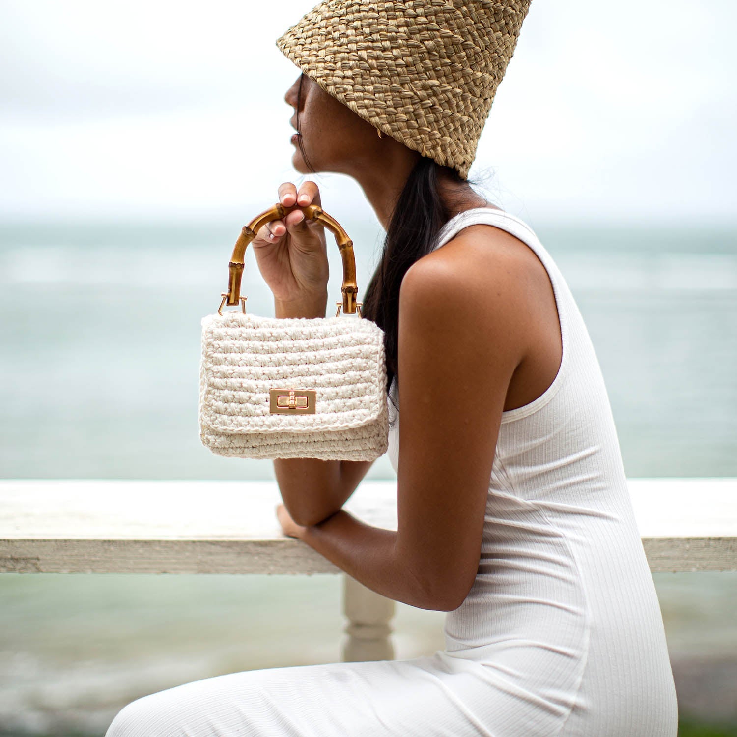 Woman holding a textured handbag by the beach