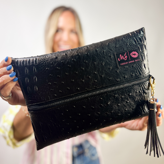 Black textured clutch bag with a brand logo held by a person.