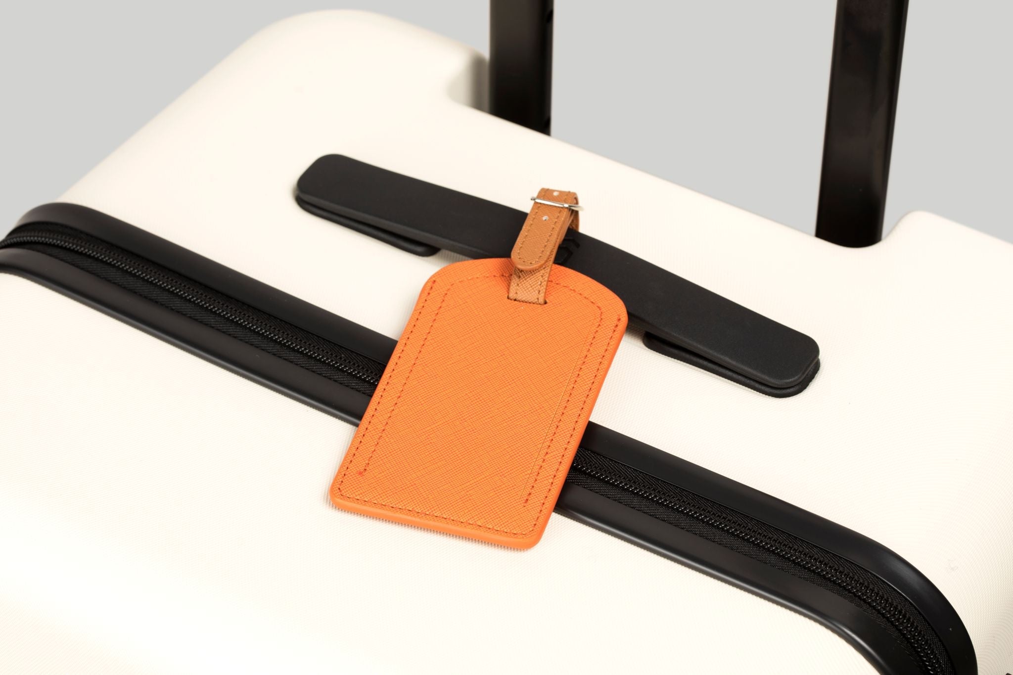 Orange luggage tag attached to a black suitcase handle.