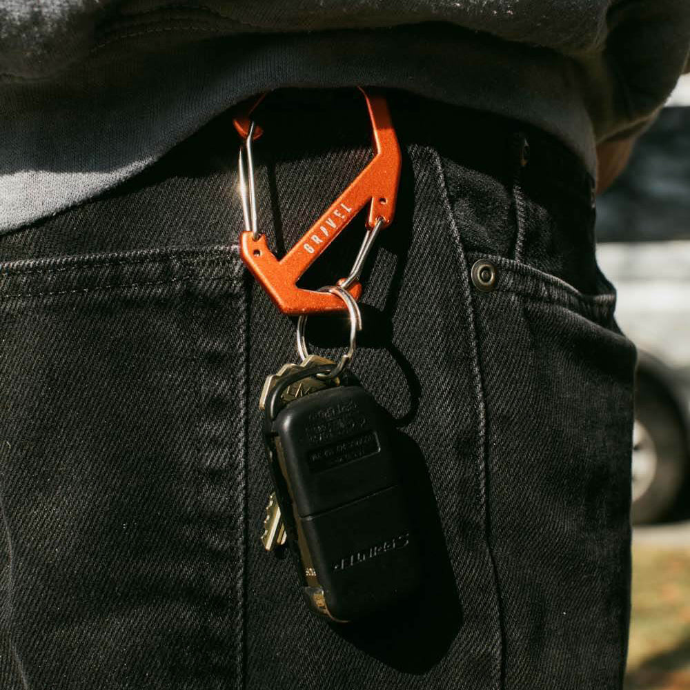 Orange carabiner with keys attached to a person's jeans pocket.