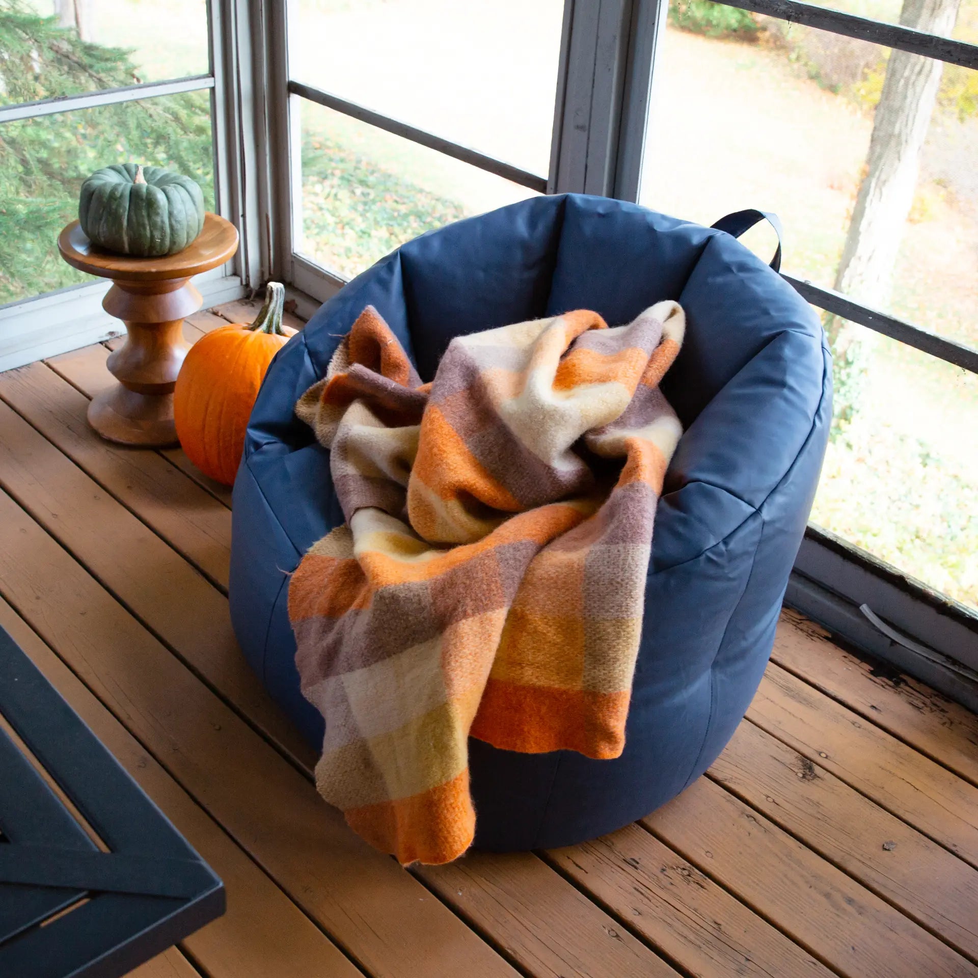 Blue bean bag chair with a plaid blanket on a wooden deck