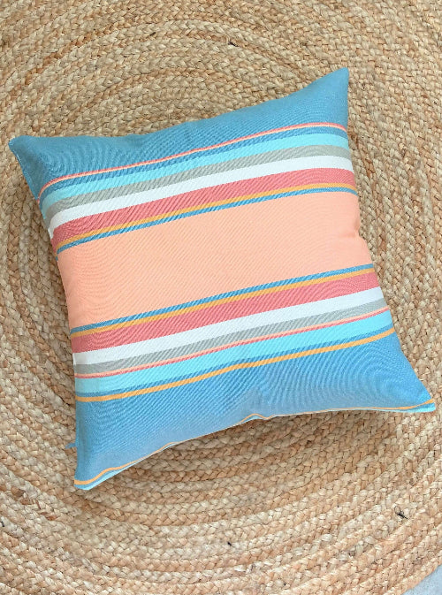 Striped pillow with blue, pink, and multicolor pattern on a textured surface