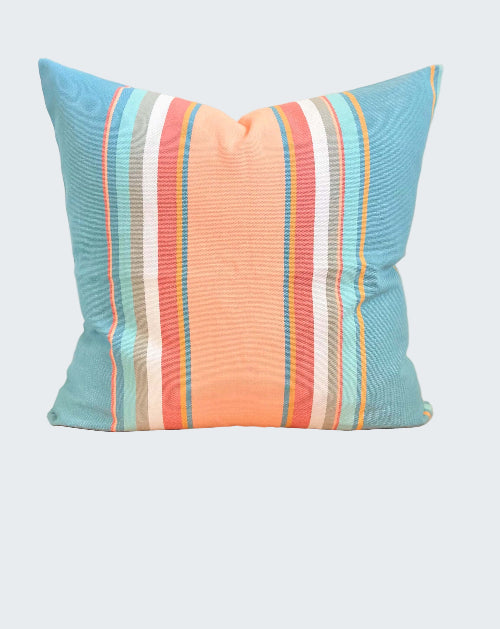 Striped pillow with blue, orange, and white colors on a wooden stool.