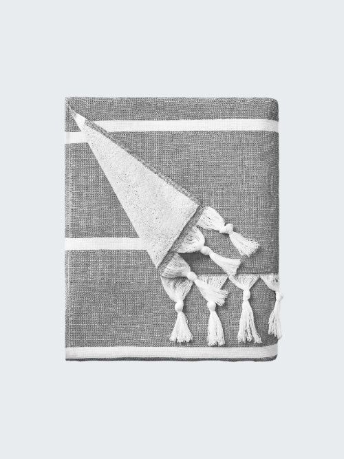 Gray towel with a white geometric design and tassels on a white background