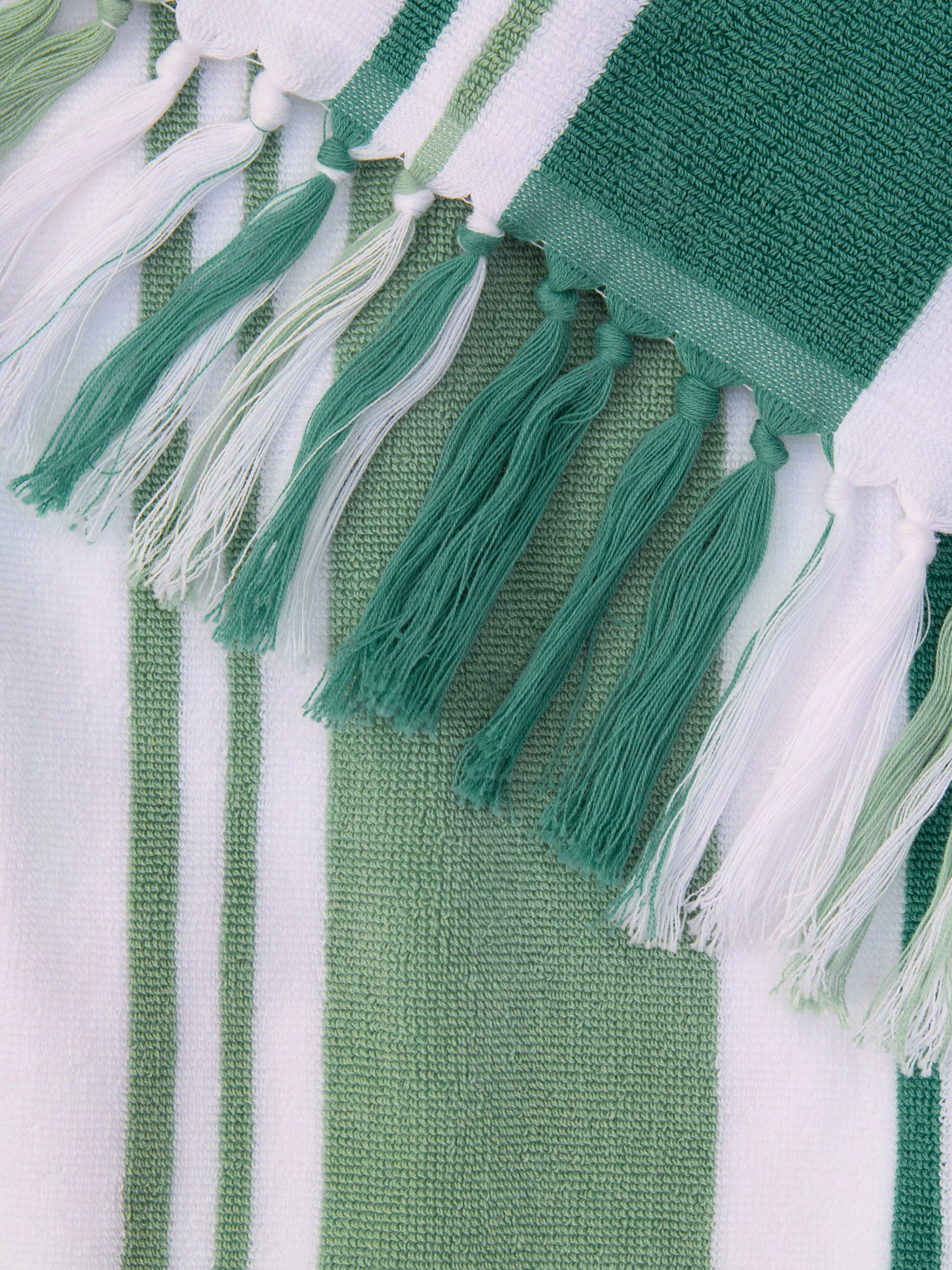 Green and white striped fabric with tassels on a white background