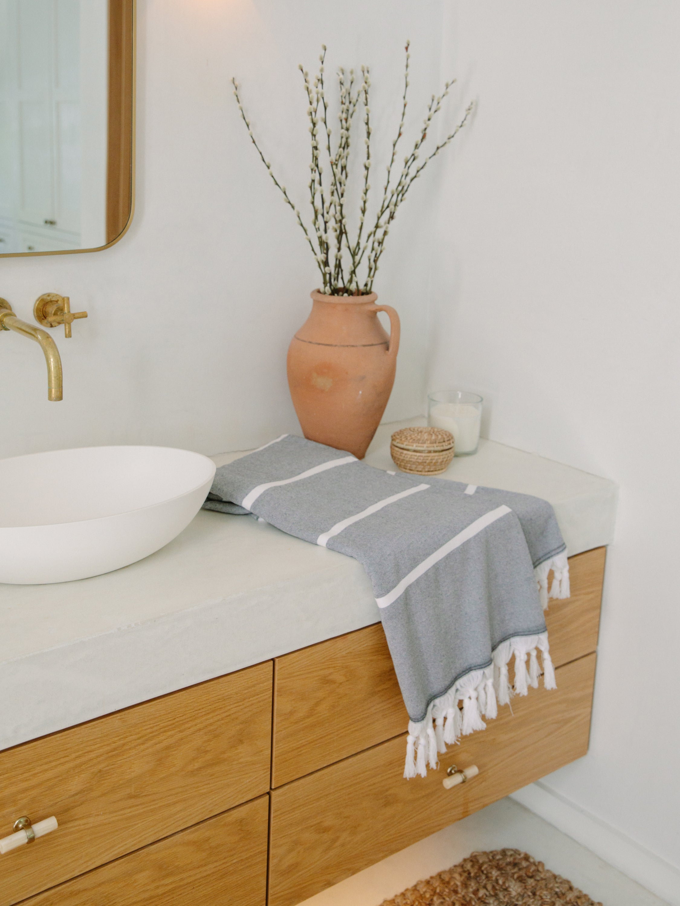 Bathroom with wooden vanity, white sink, and terracotta vase with branches.