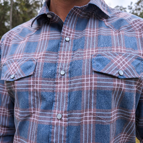 Close-up of a blue and pink plaid shirt with buttons.