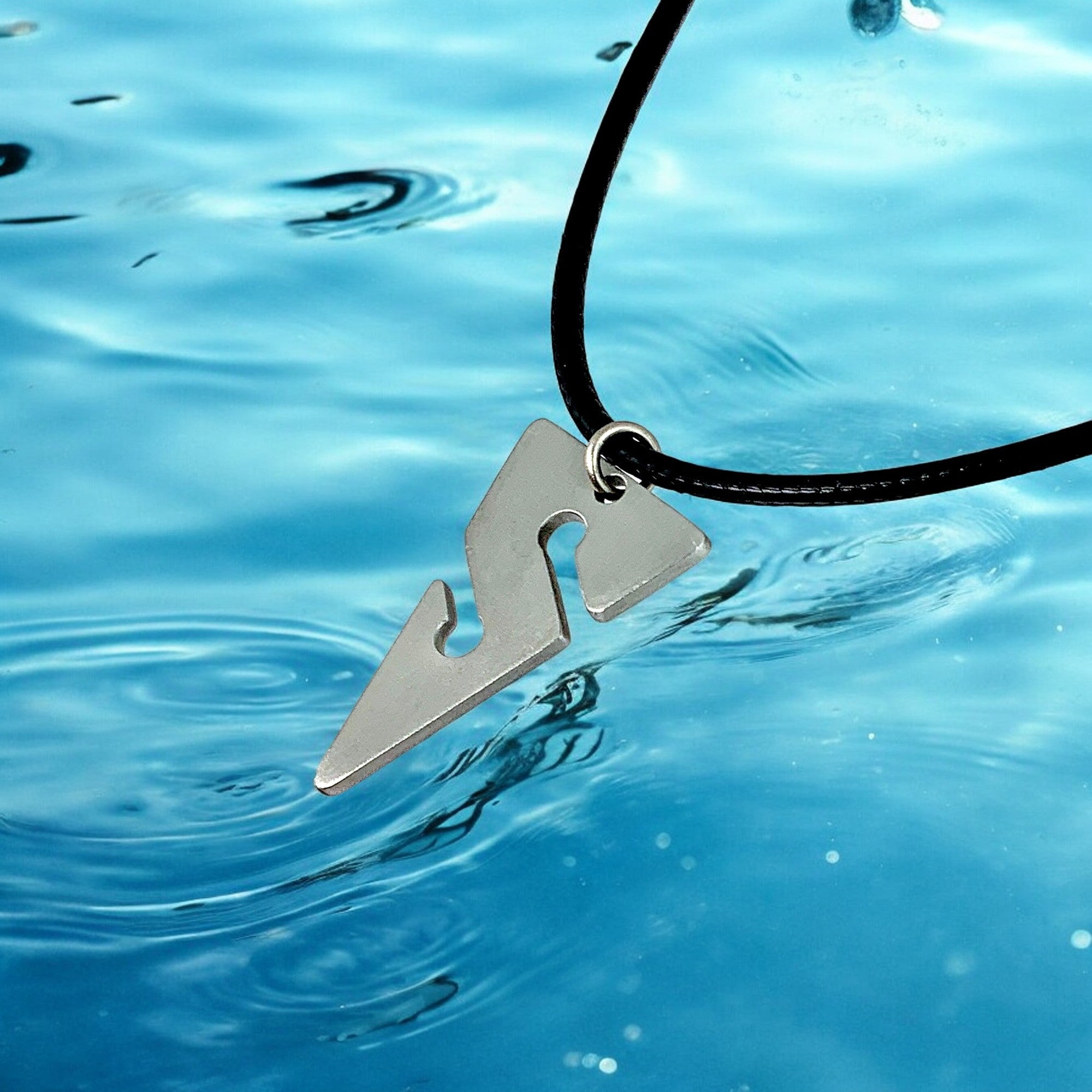 Metallic pendant on a black cord over blue water