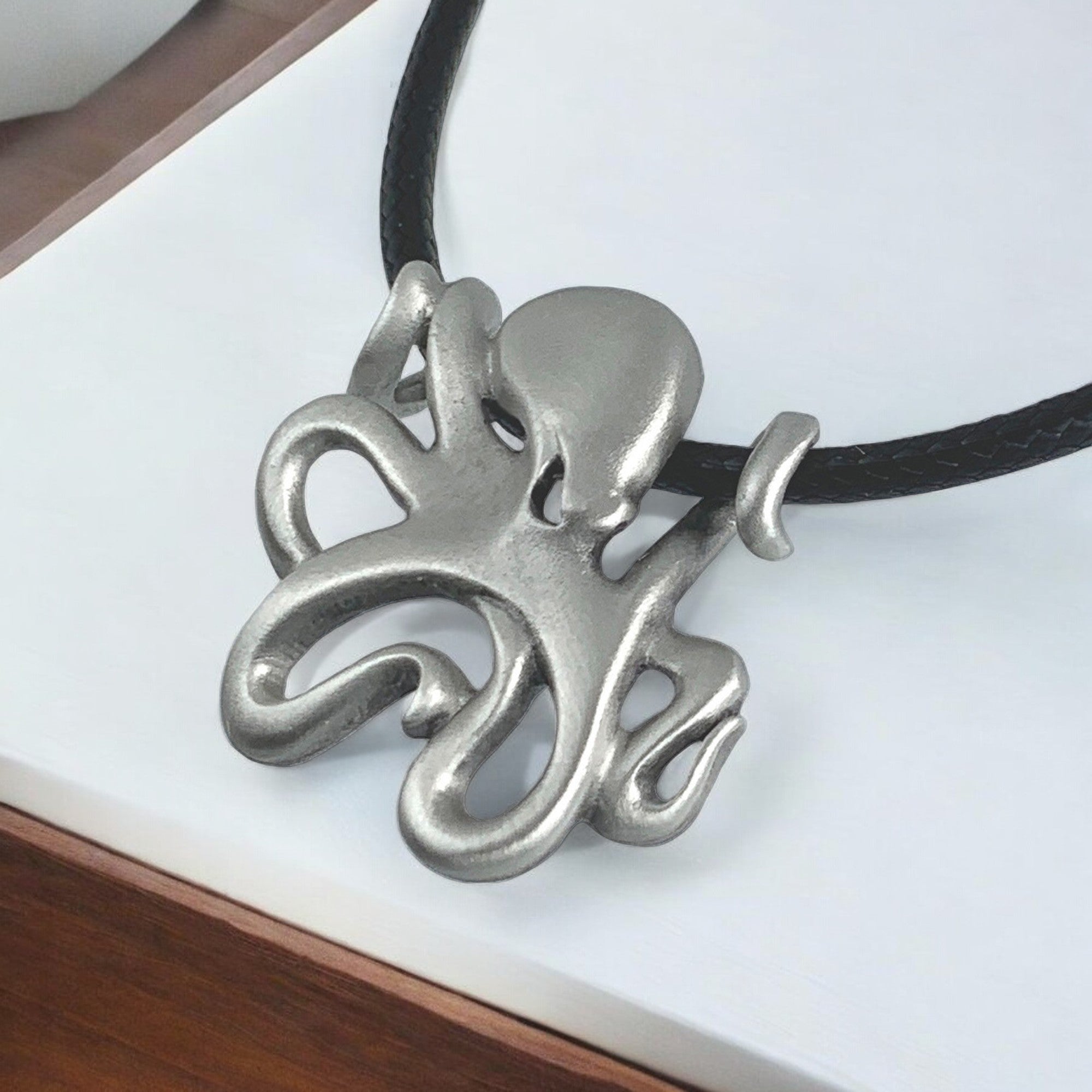 Silver octopus pendant on a black cord against a white background