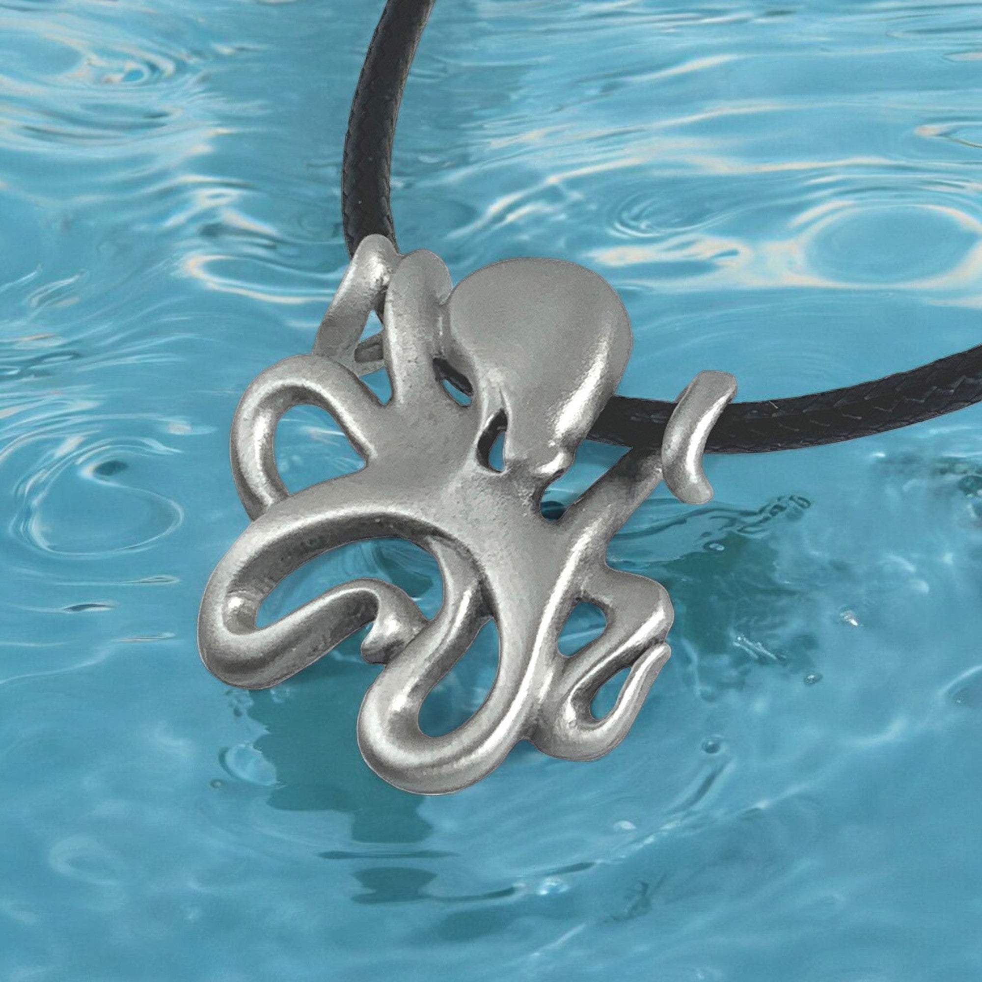Silver octopus pendant on a black cord against a blue water background