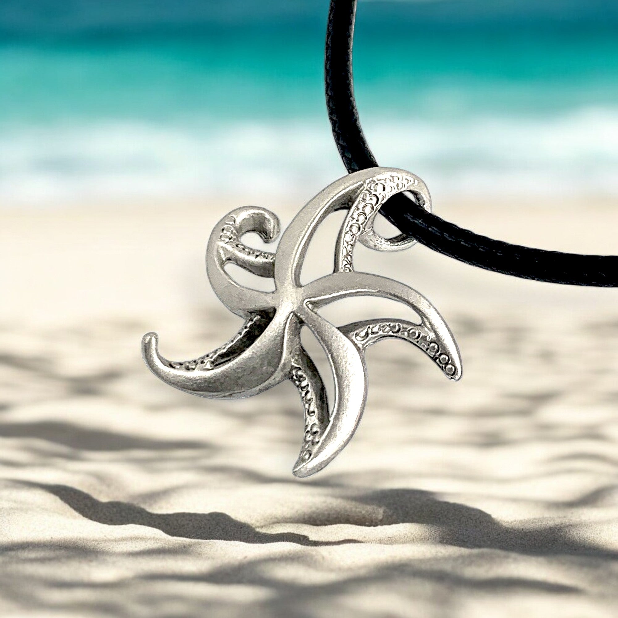 Silver starfish pendant on a black cord with a beach background