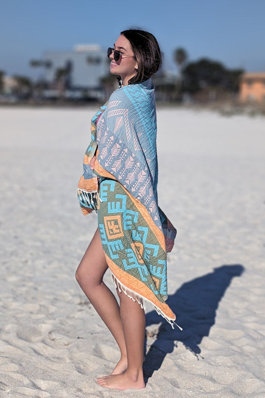 Woman on a beach wearing a colorful patterned towel