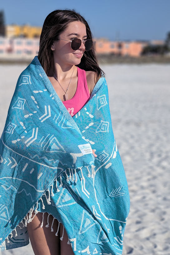 Woman on a beach wrapped in a blue patterned towel