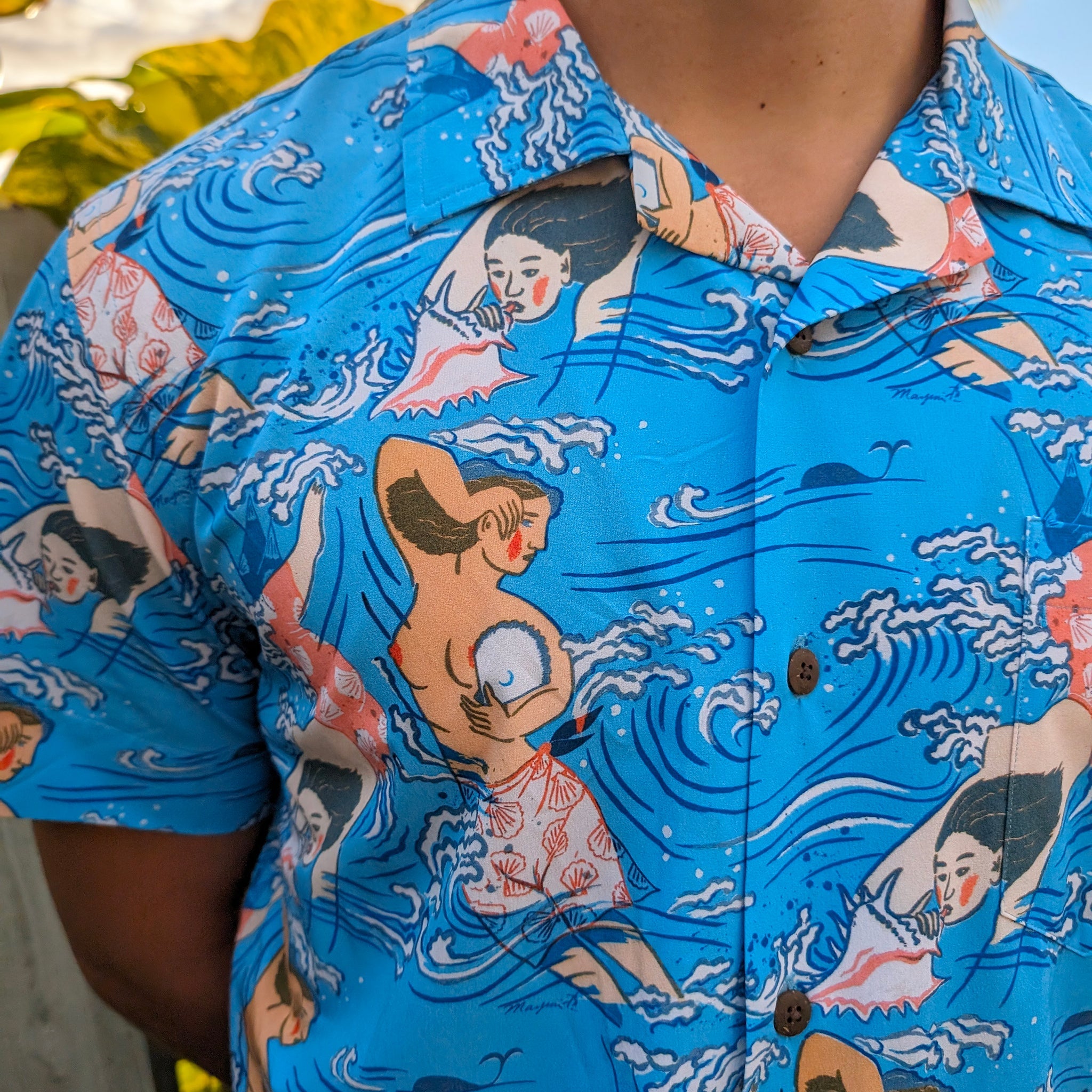 Blue Hawaiian shirt with vintage-style graphics of women and fish.