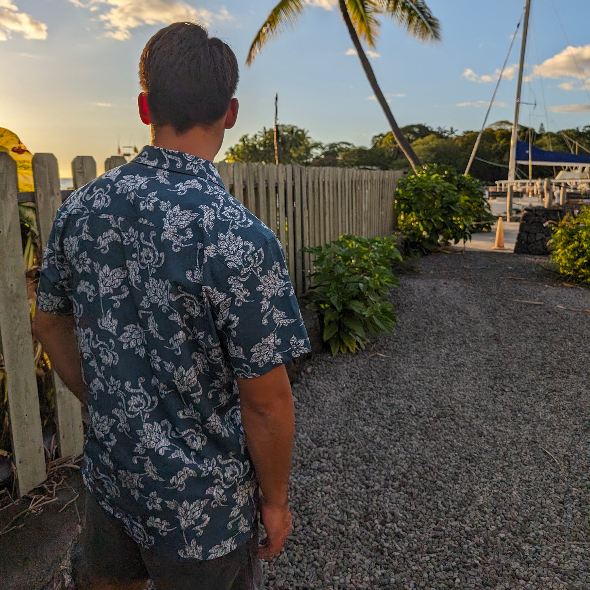 Man in a floral shirt standing on a path with a scenic background