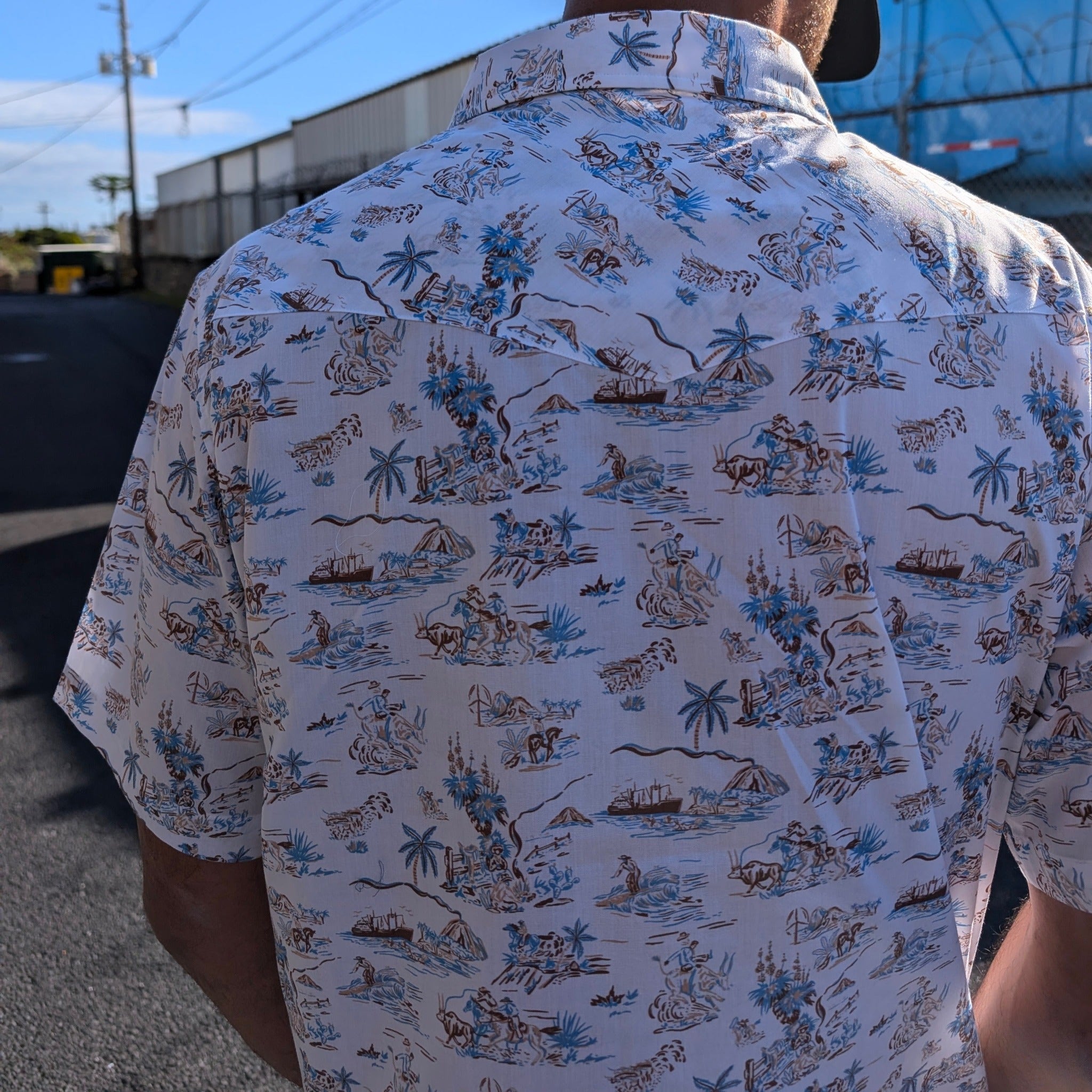 Person wearing a patterned shirt with a tropical design outdoors.