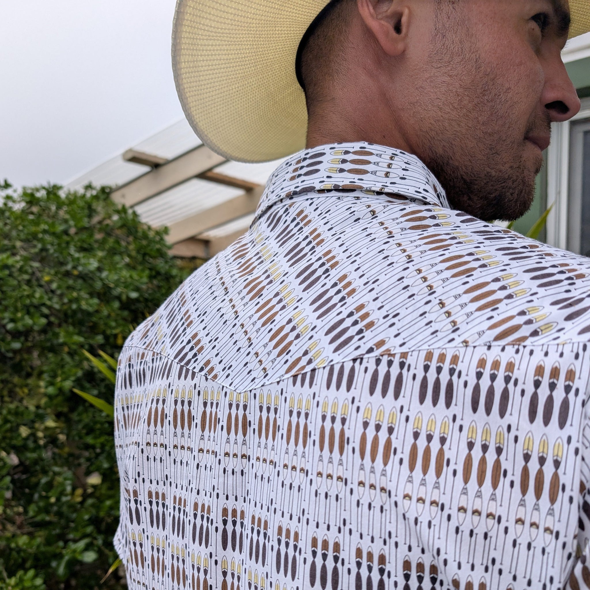 Man wearing a patterned shirt and straw hat outdoors
