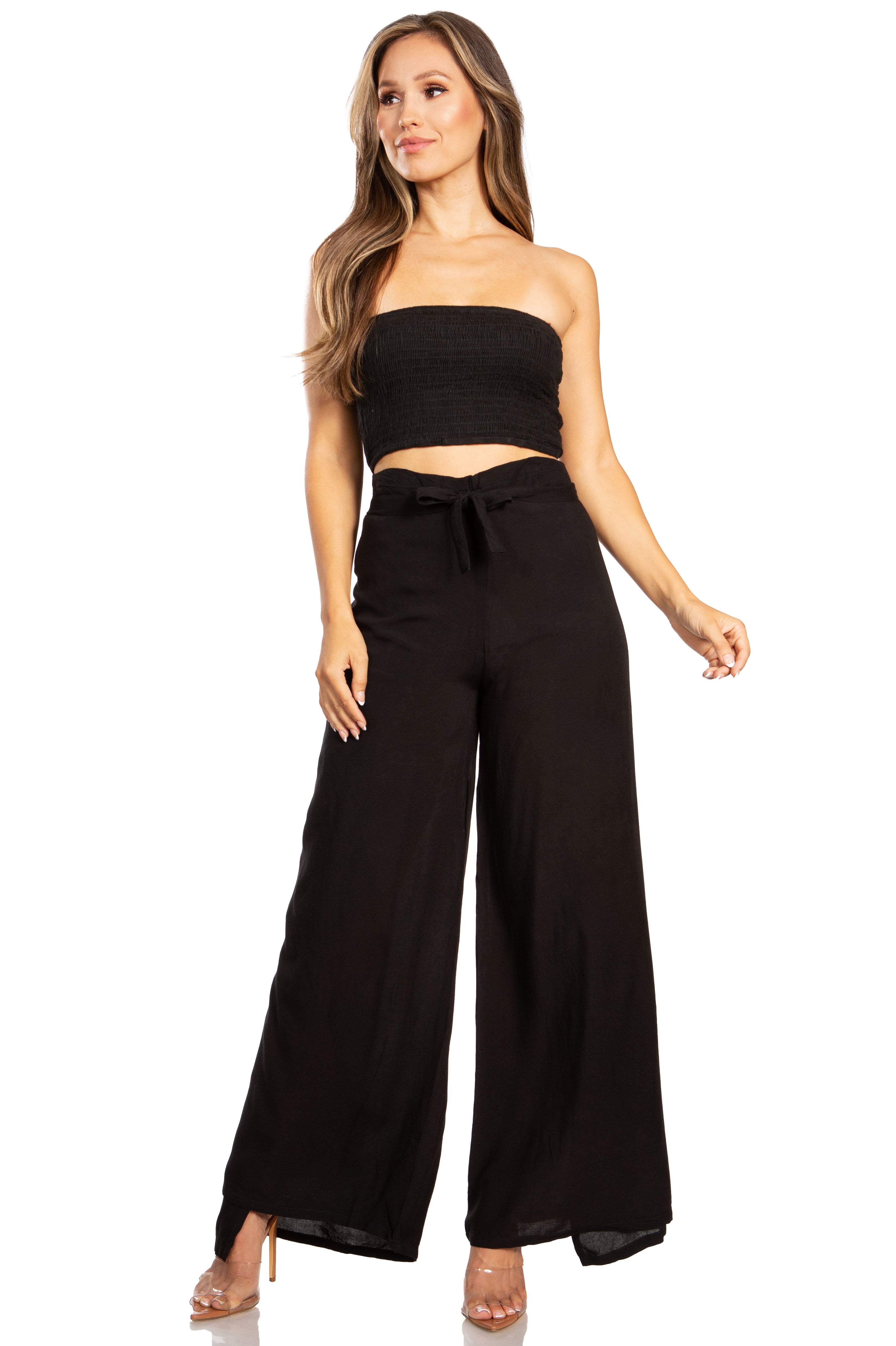 Woman wearing a black strapless top and wide-leg pants on a white background
