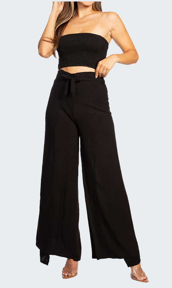 Woman wearing a black strapless top and wide-leg pants on a white background