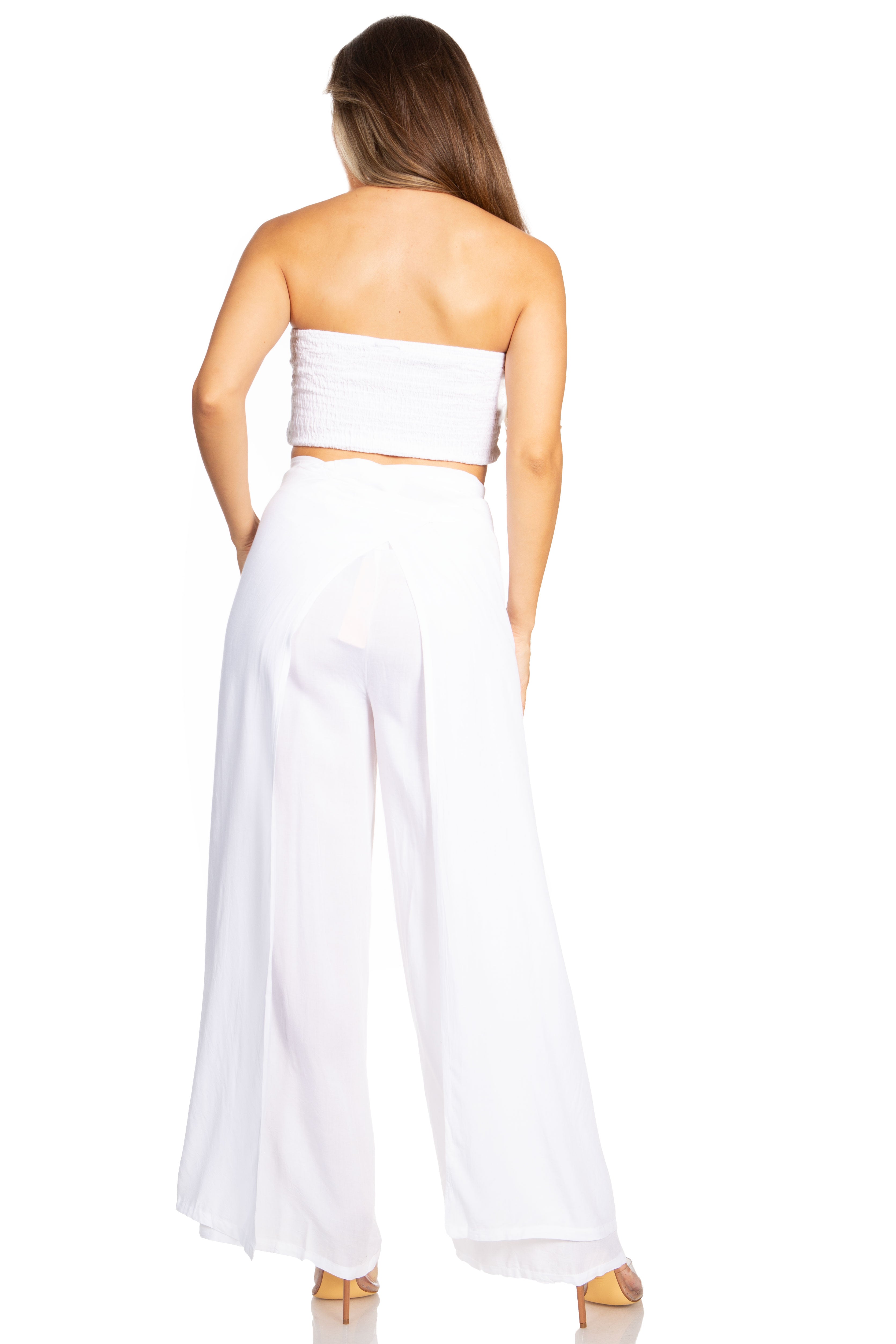 Woman wearing a white strapless top and wide-leg pants on a white background