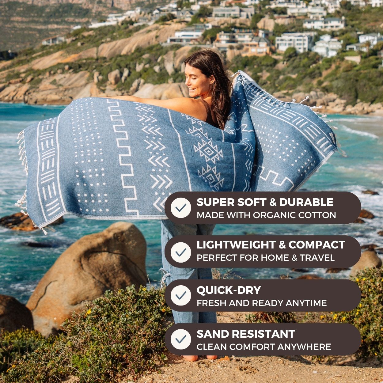 Person holding a blue patterned towel by the ocean with product features listed.