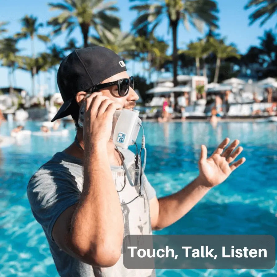 Man talking on a phone by a pool with palm trees in the background