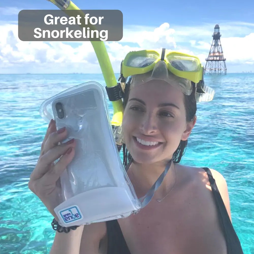 Woman holding a phone case with snorkeling gear, lighthouse in the background