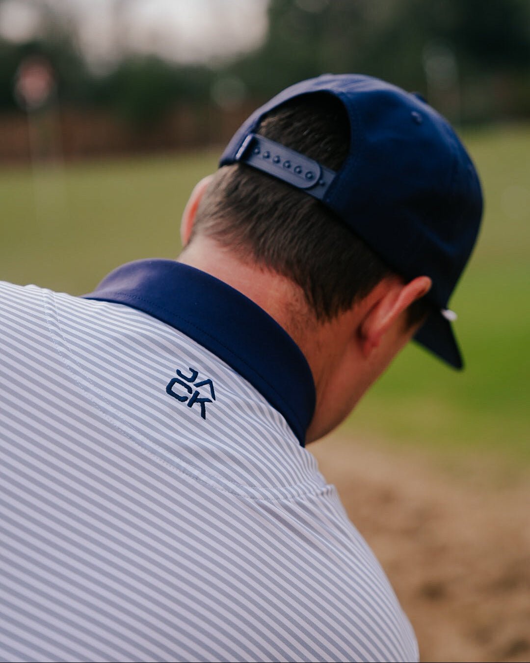 Person wearing a blue cap and striped shirt on a blurred outdoor background