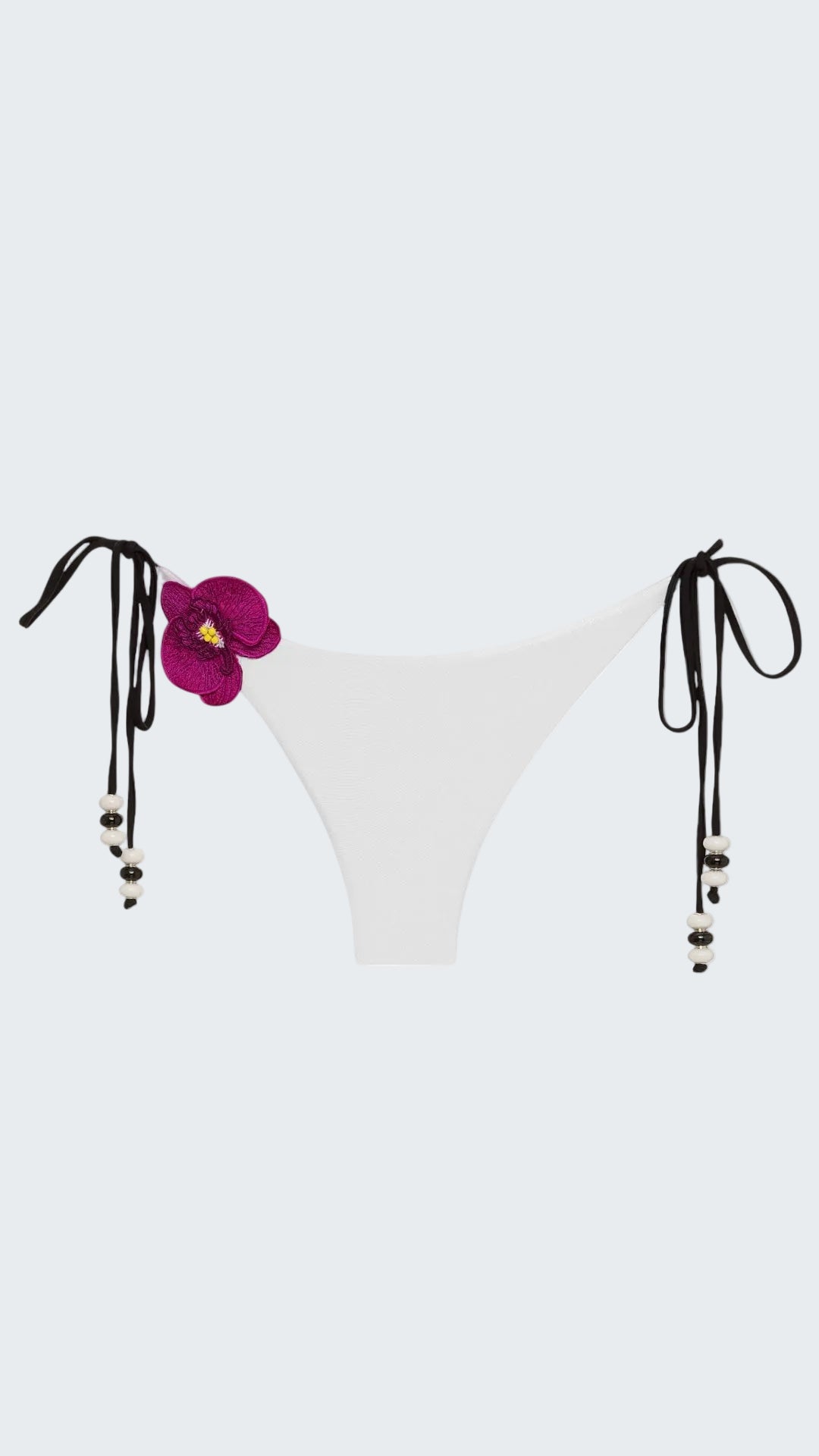 White bikini bottom with floral design and black straps on a white background
