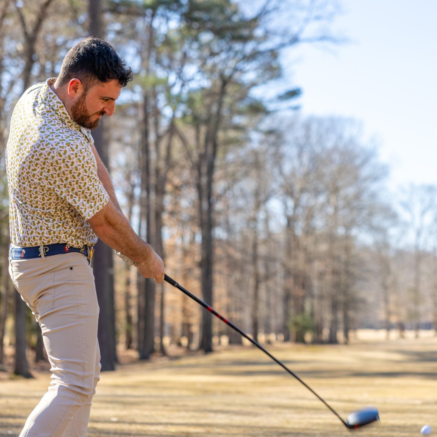 Man playing golf on a course with trees in the background