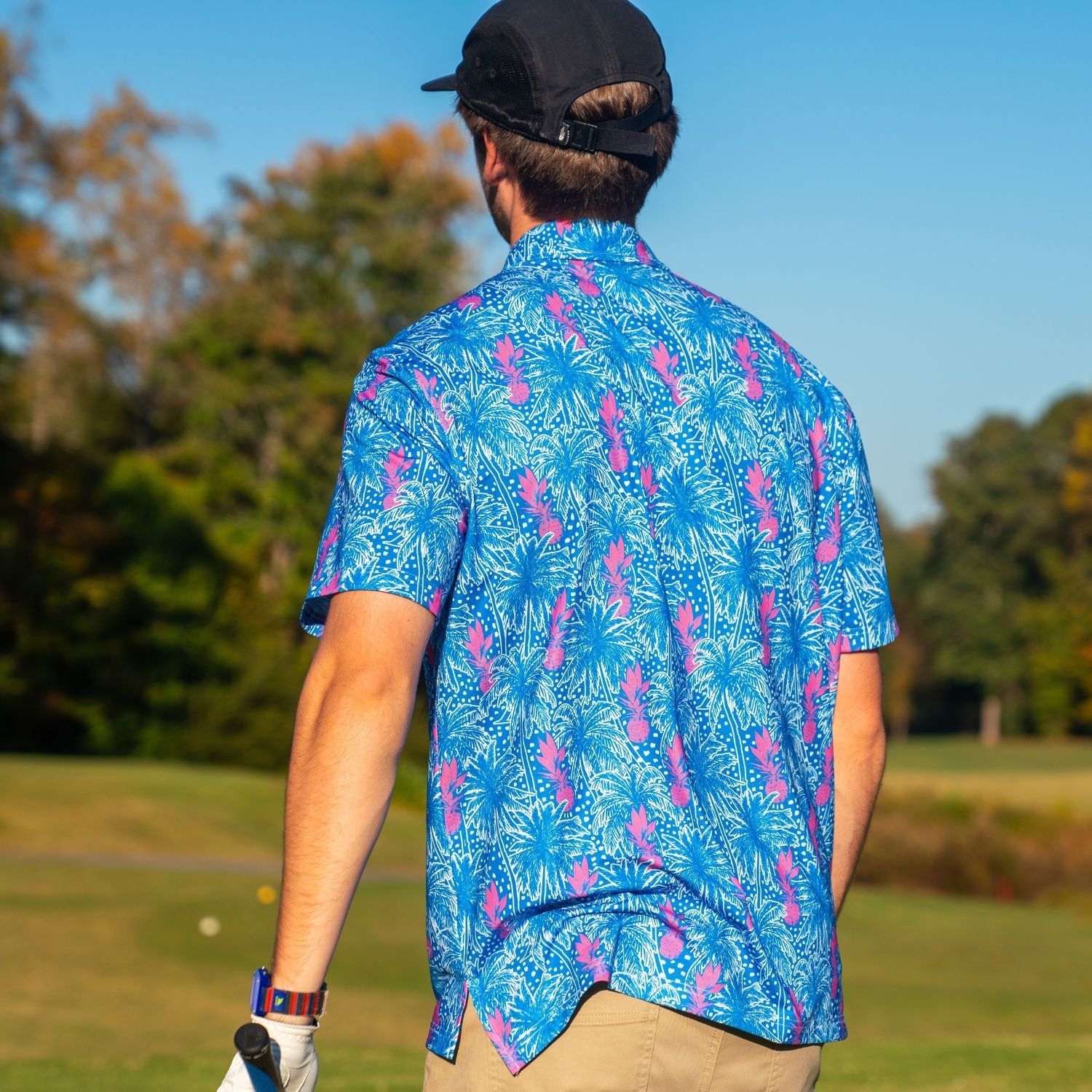 Person wearing a blue and pink patterned shirt on a golf course
