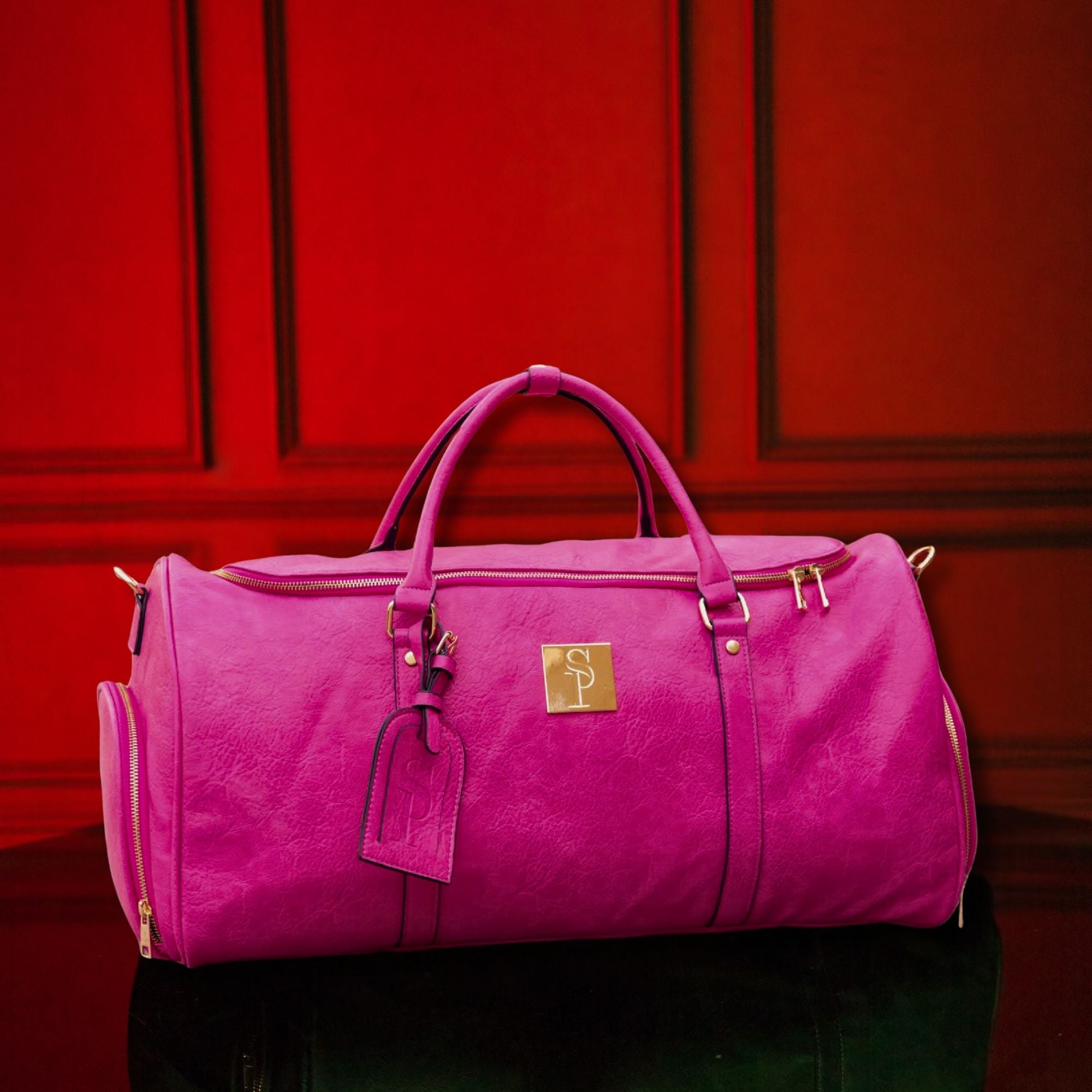 Pink duffel bag with a gold tag against a red background