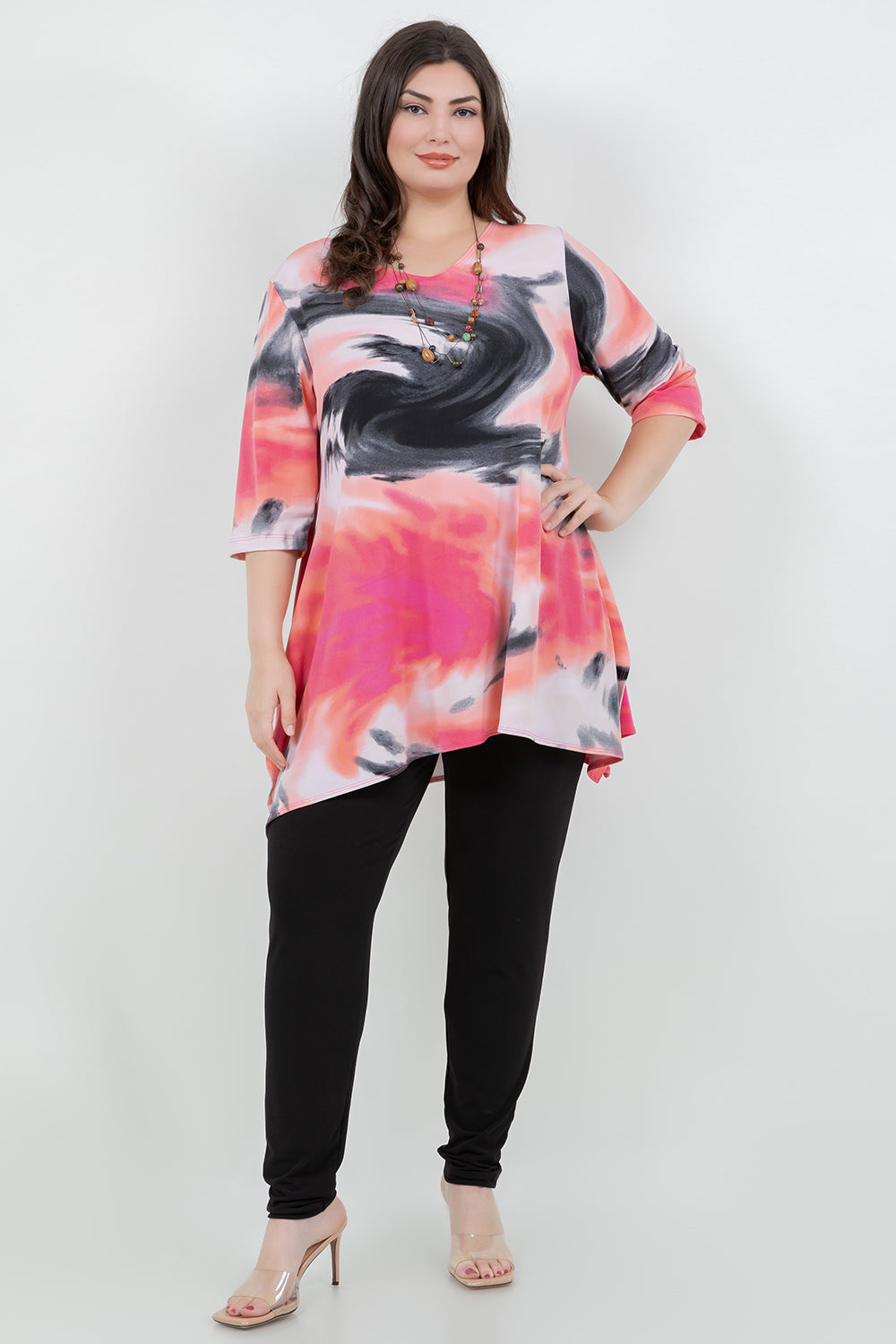 Woman wearing a colorful tie-dye top and black pants on a white background