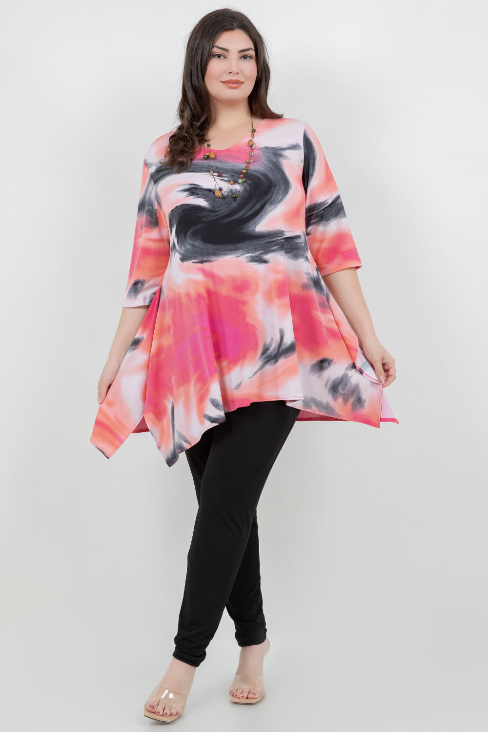 Woman wearing a colorful abstract patterned top and black pants on a white background