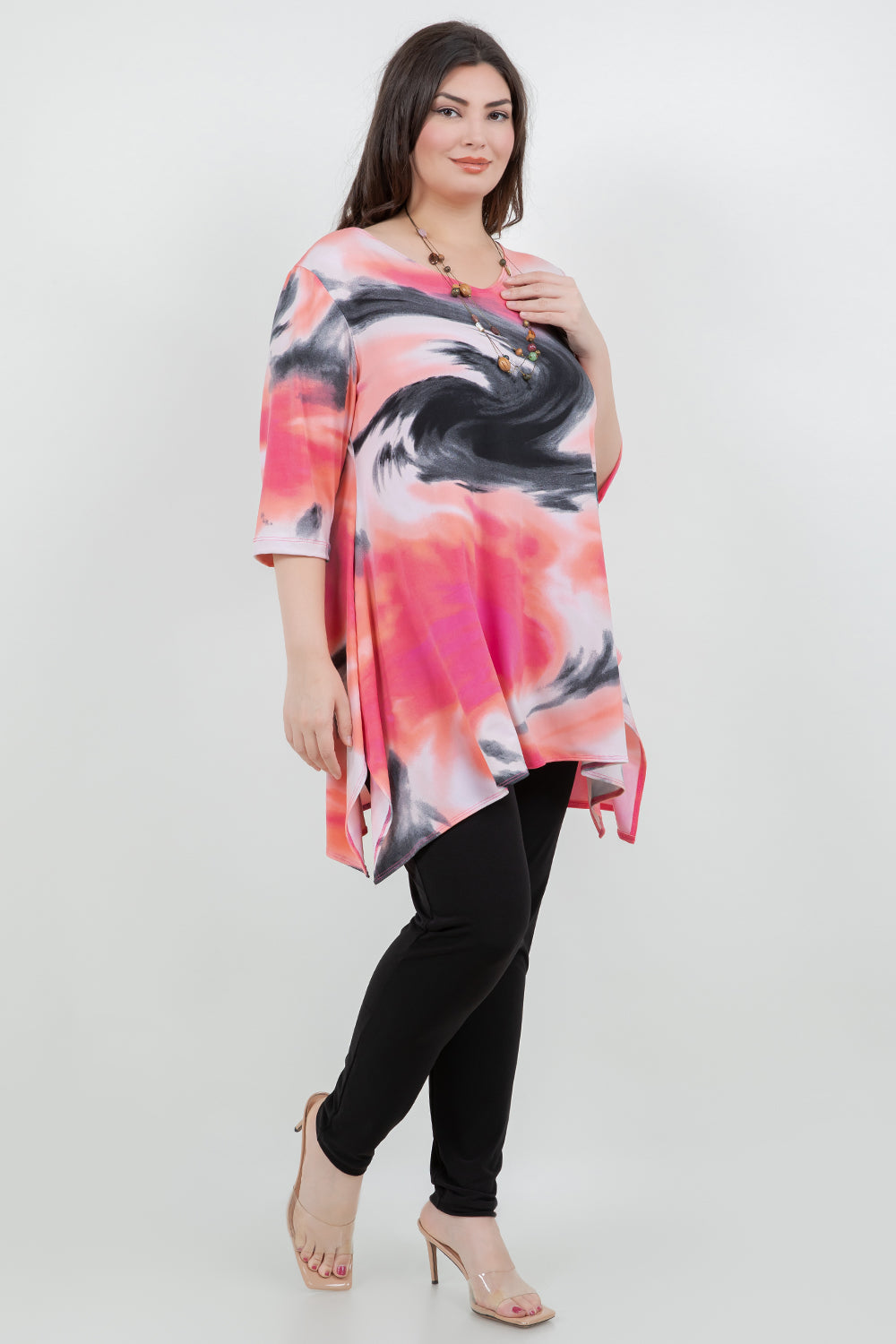 Woman wearing a colorful tie-dye top and black pants on a white background
