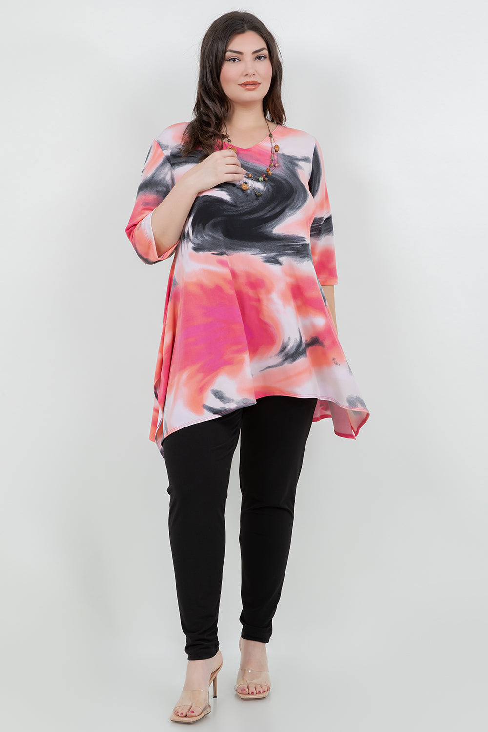 Woman wearing a colorful dress with black leggings on a white background