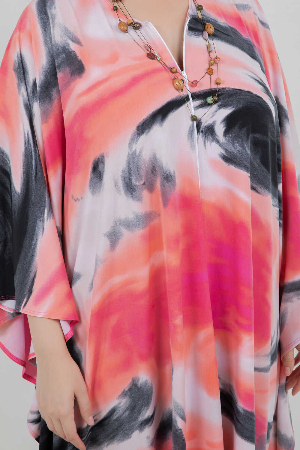 Colorful abstract patterned garment with a necklace on a plain background