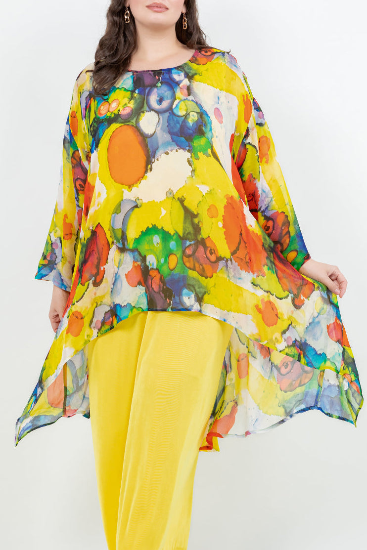 Woman wearing a colorful floral top and yellow pants on a white background