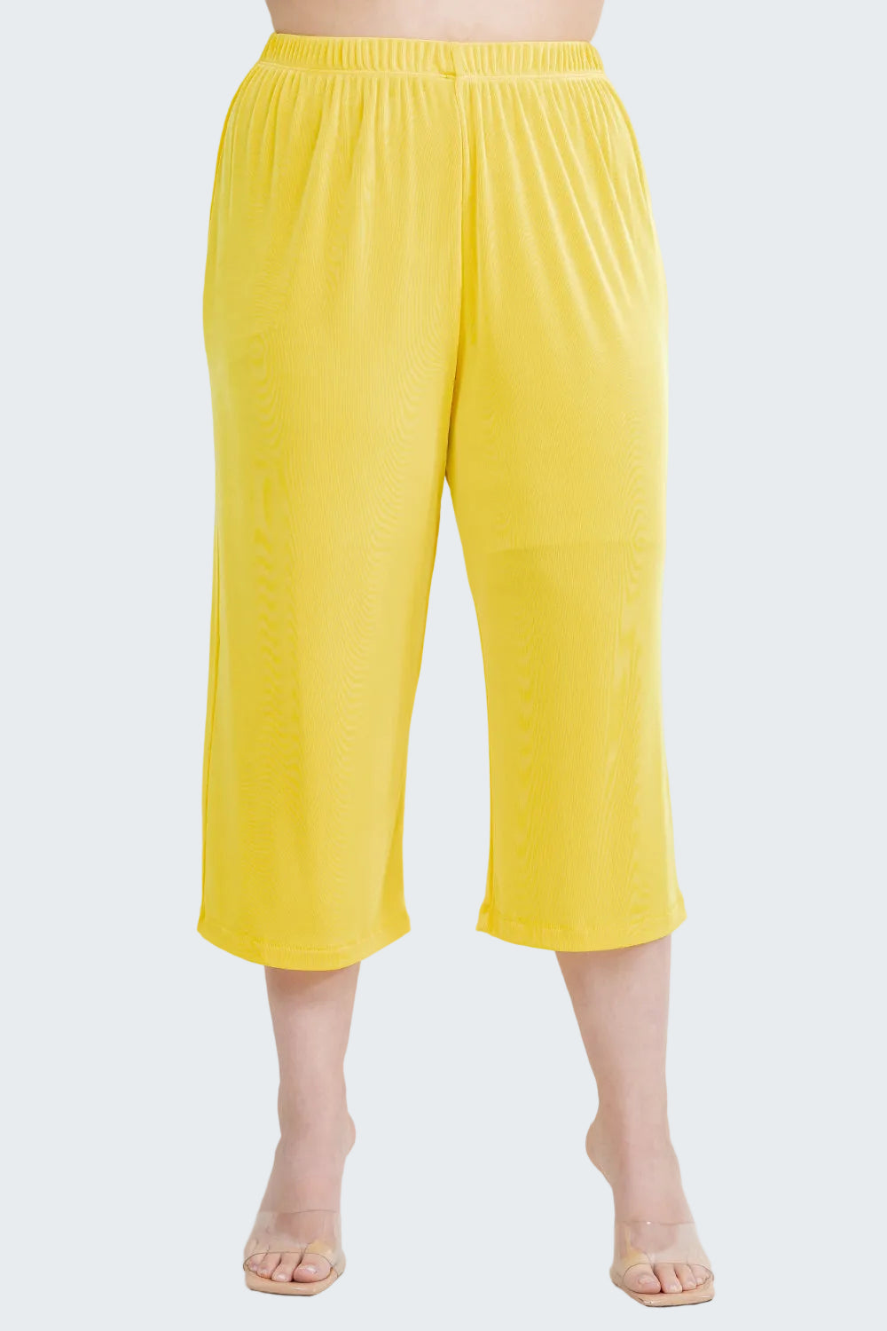 Yellow capri pants worn by a person on a white background