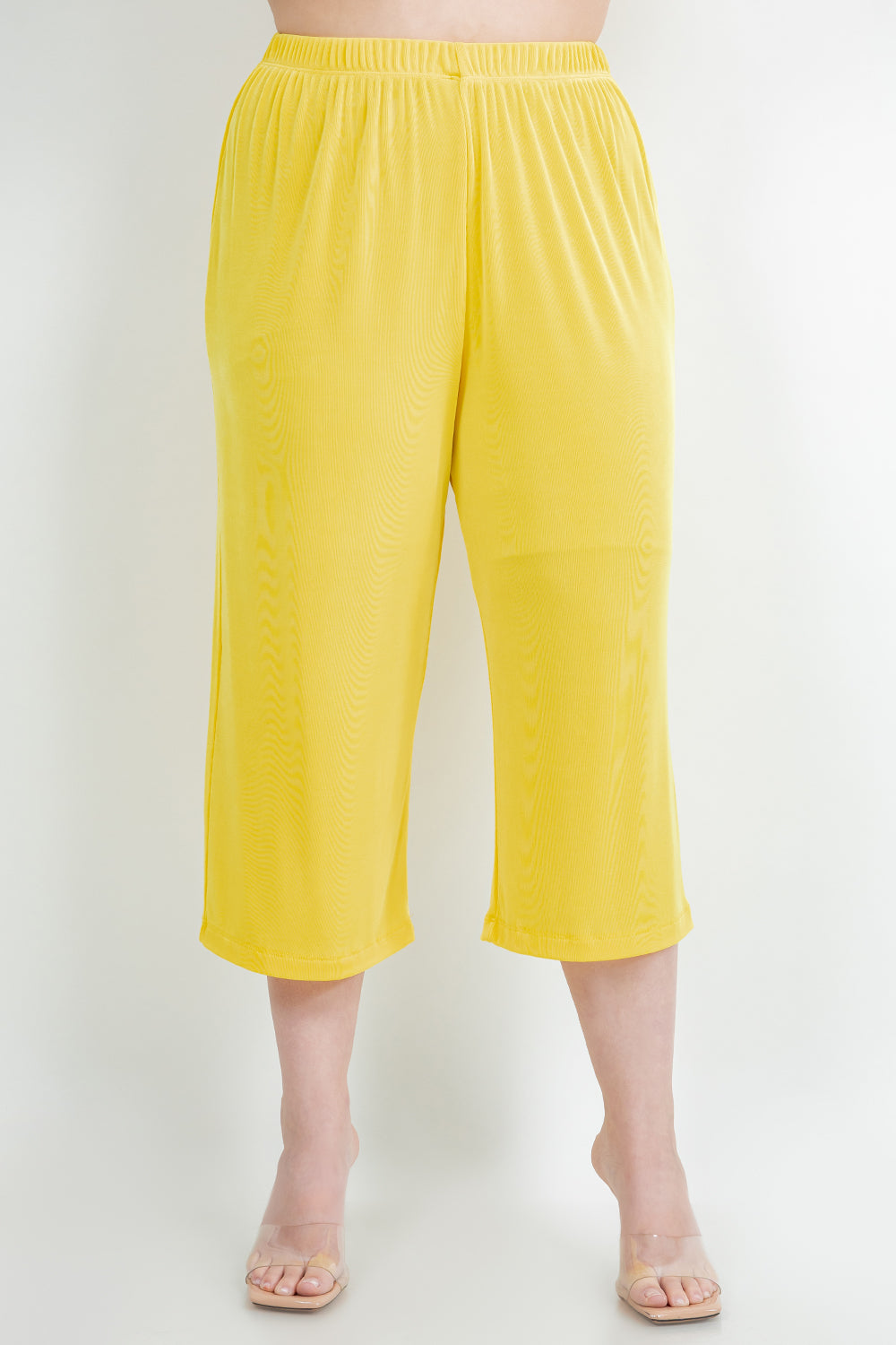 Yellow capri pants worn by a person on a white background