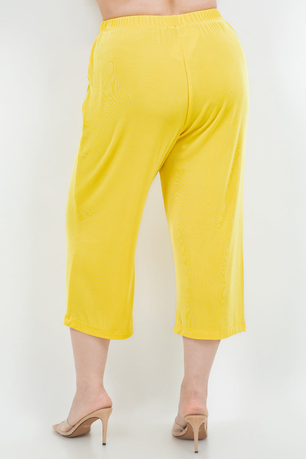 Yellow capri pants worn by a person on a white background