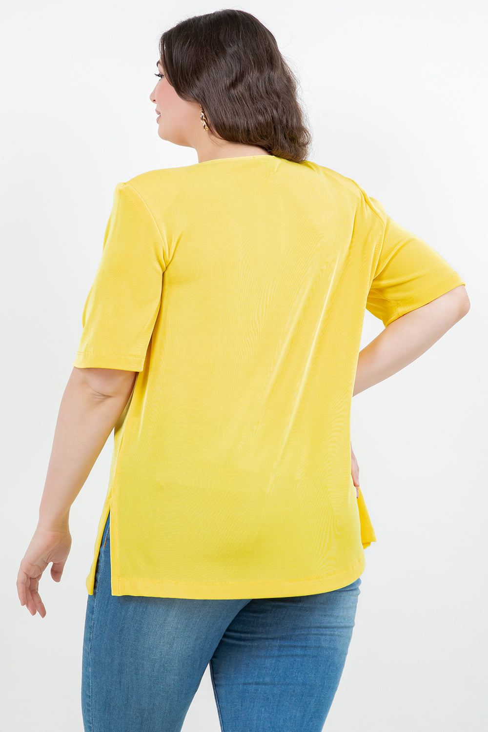 Woman wearing a yellow top and blue jeans on a white background
