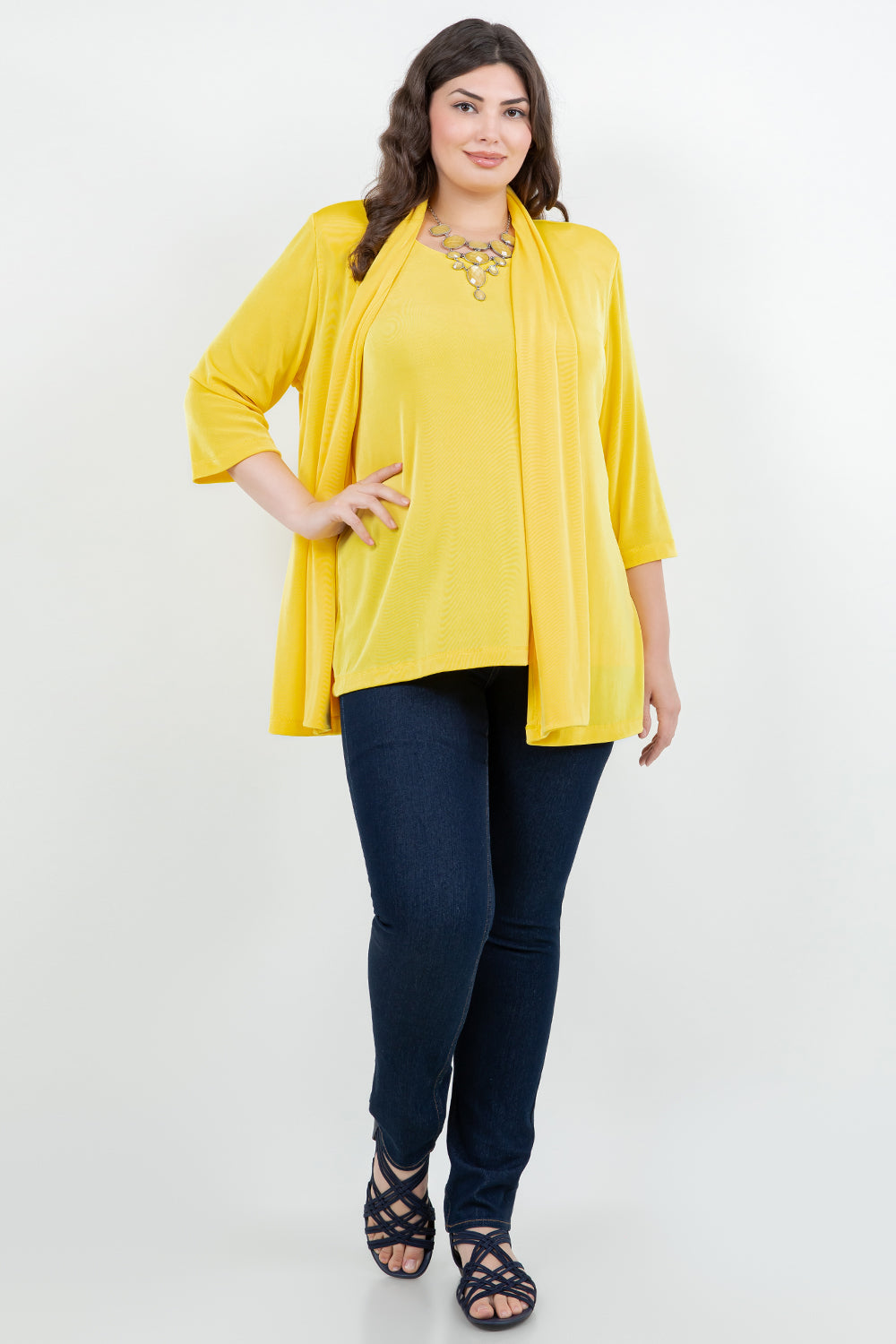 Woman wearing a yellow top and navy pants on a white background