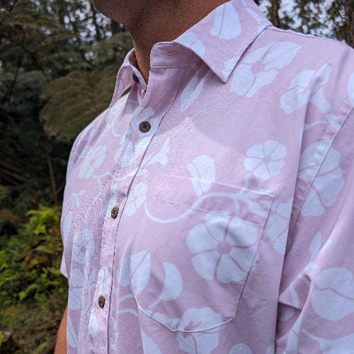 Close-up of a person wearing a pink floral shirt with a blurred natural background