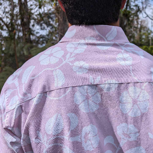 Person wearing a pink floral shirt with a blurred natural background