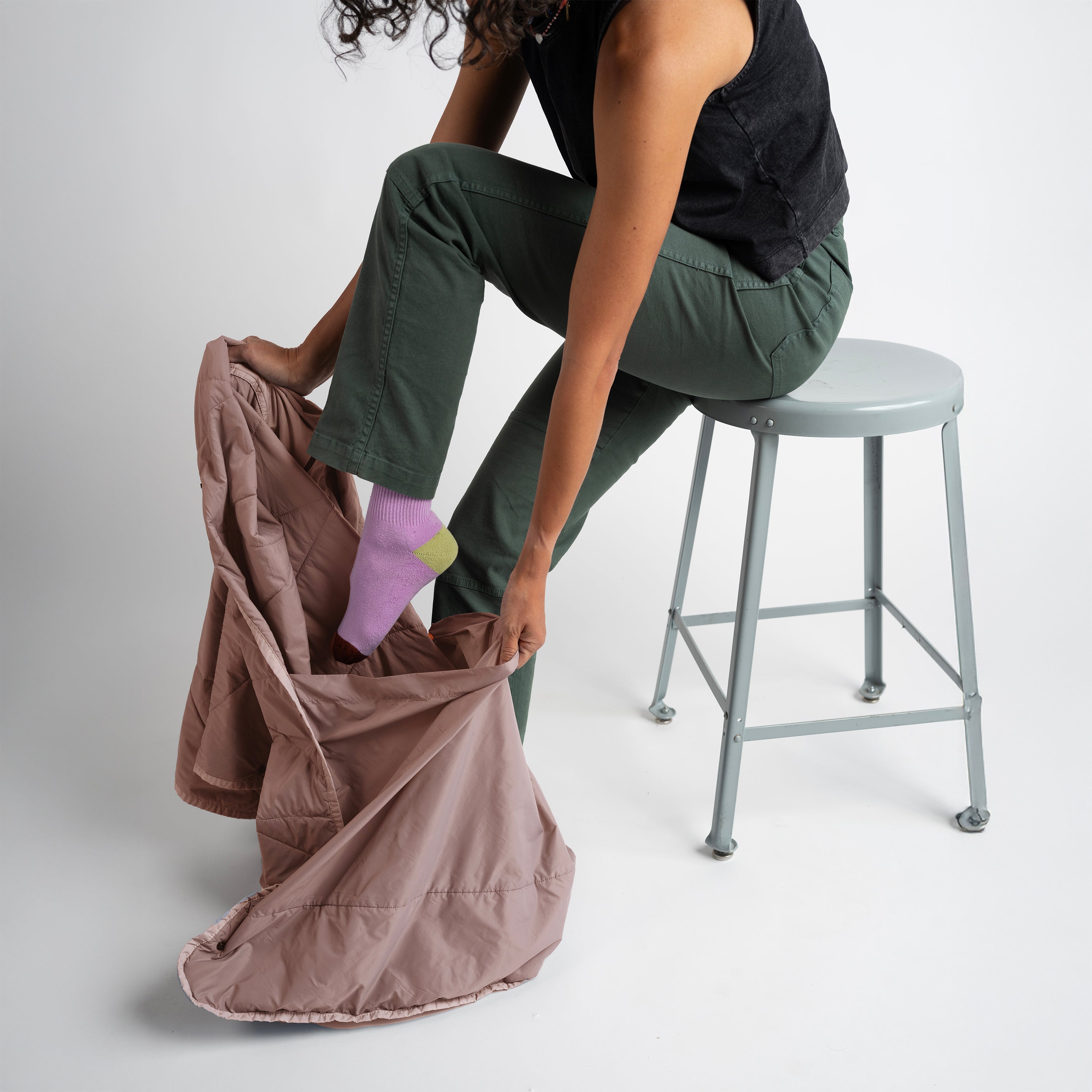 Person sitting on a stool holding a brown bag against a white background