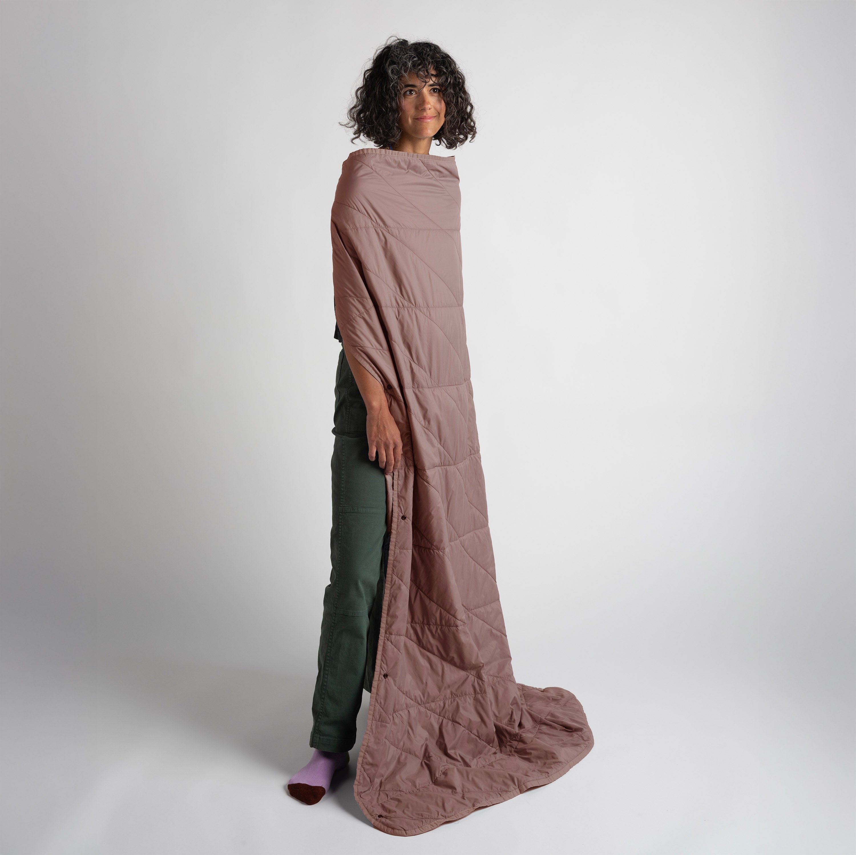 Person wearing a long, brown quilted garment against a white background