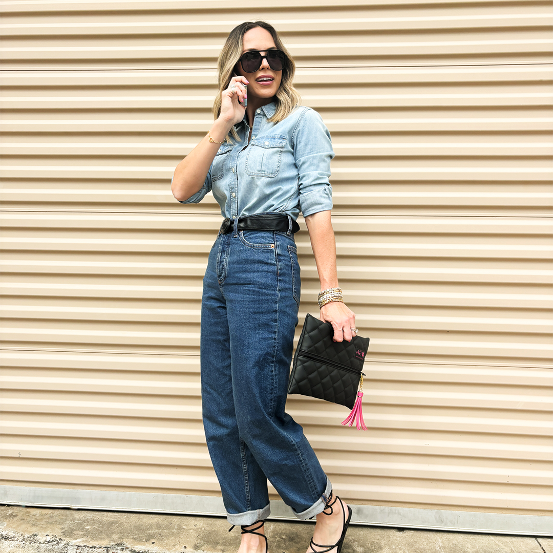 Woman in denim outfit standing against a beige wall