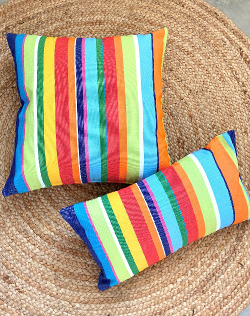 Two colorful striped pillows on a woven surface