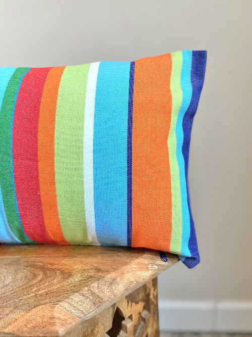 Colorful striped pillow on a wooden surface with a neutral background